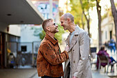 Happy gay couple face to face on city sidewalk