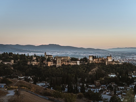 Granada, Andalucia, Spain - September 9, 2023: Panoramic view of the castle Alhambra in Granada, Andalusia, Spain, during sunset, from the Mirador de la Cruz de Rauda, golden hour, clear sky, sunlight
