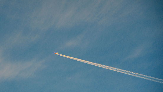 Flying airplane leaving trails in the blue sky