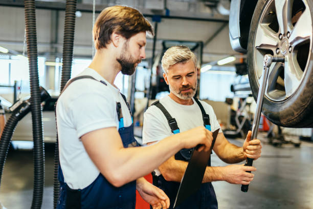istock Portrait two handsome different age auto mechanics in uniform standing together at the car service. Father and son working together. Family business concept.v 1945215168