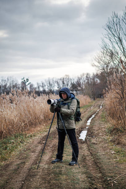 istock Photographer is setting up camera on tripod outdoors 1945223451