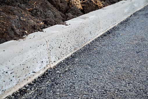 Asphalt-curb joint, laying new road surface, concrete curb, roadbed, black bitumen on the road. High quality photo