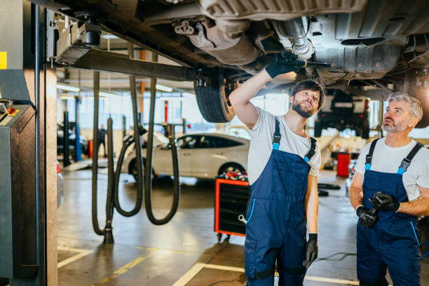 istock Experienced mechanic staring at the car underside vehicle on a lift in service using a LED lamp. Two car mechanic diagnosing vehicle at the auto service. Vehicle raised on lift at maintenance station. 1945235514