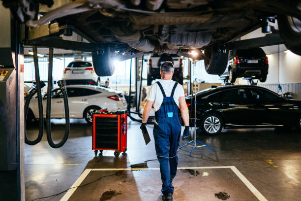 istock Rear view of car mechanic in Auto service. Professional middle age master performs maintenance, oil change, computer diagnostics, replacement of auto parts, repair of brake system. 1945249539