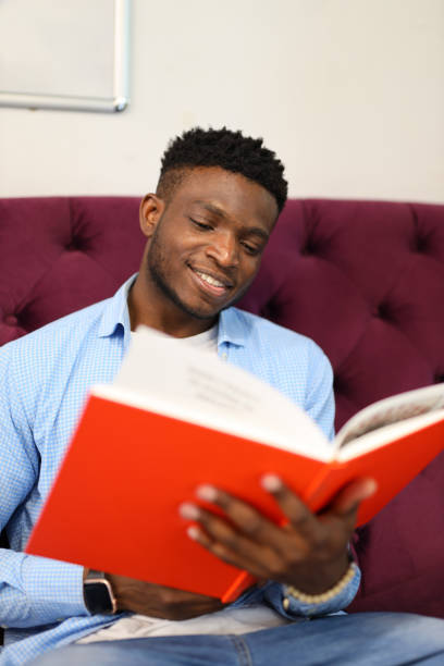istock Young man happily studying, surrounded by books in a comfortable indoor setting, embracing the joy of learning. 1945263865