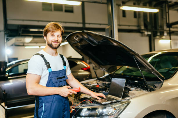 istock Handsome caucasian tectrician man testing car with multimeter at garage or car service. Car service, repair, maintenance and people concept. 1945279089