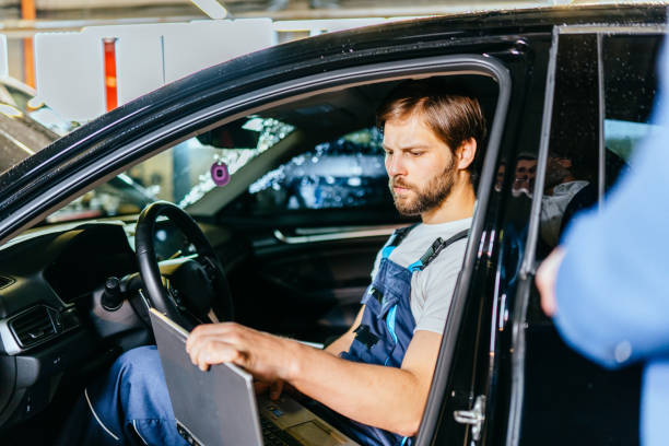 istock Focused mechanic looking for engine problem using laptop at car service. Repair, maintenance and people concept. 1945279648