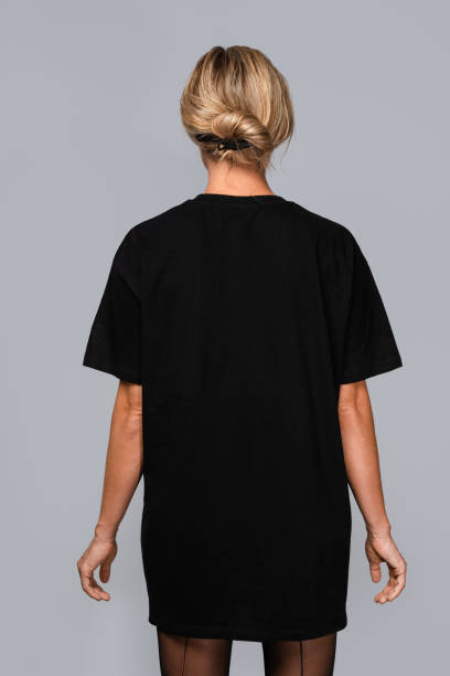 istock Woman dressed in a black oversized t-shirt with blank space, ideal for a mockup, set against gray background 1945280706