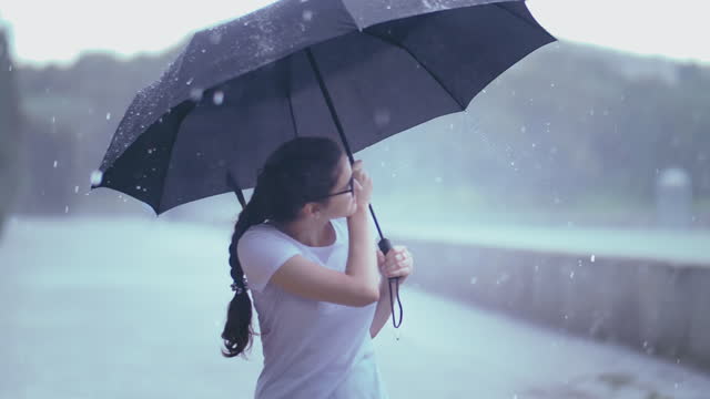 Rainy Bliss: Young Girl's Delight Under Umbrella in Downpour