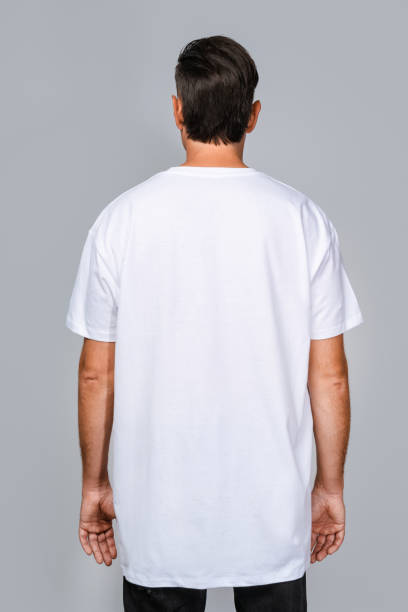 istock Man dressed in a white oversized t-shirt with blank space, ideal for a mockup, set against gray background 1945288712