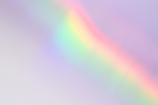 Abstract holographic retro rainbow light refraction texture overlay. Organic drop diagonal holographic flare on a white wall background. Natural shadows and light effect