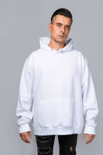 istock Man dressed in a white oversized hoodie with blank space, ideal for a mockup, set against gray background 1945290339