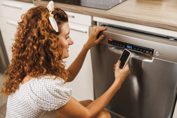 istock Woman With Phone And Dishwasher 1945292970