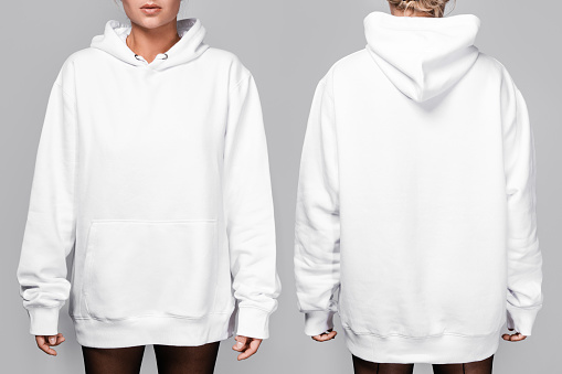 Front and back views of a woman wearing a white, oversized hoodie with blank space, ideal for a mockup, set against gray background.