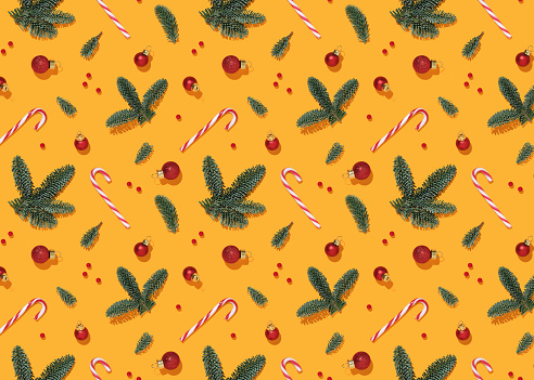 Yellow Christmas background with fir branches, baubles, berry and candy cane