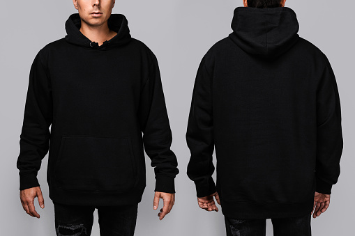 Front and back views of a man wearing a black, oversized hoodie with blank space, ideal for a mockup, set against gray background.