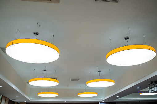 Round chandelier on the ceiling of warm light, lighting with LED lamps, interior design, office space, business room. High quality photo