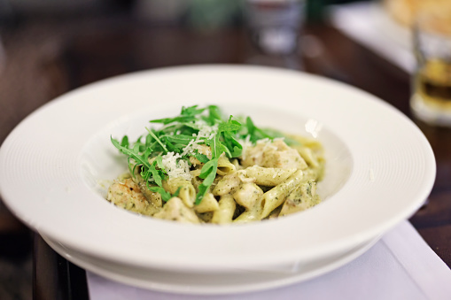 Closeup of beautifully served pasta with chicken meat and arugula.\nShot with Canon R5