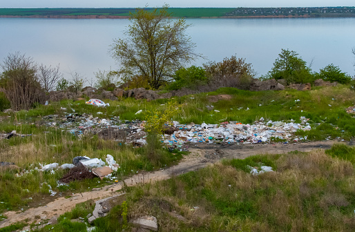 ODESSA region, UKRAINE - APRIL 30, 2017: Heaps of plastic trash on the shore of the reservoir. Ecology of nature, unorganized garbage dump