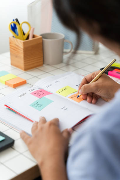 istock Person Sitting at Table, Writing on Paper 1945370920