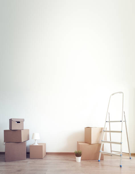 istock Different cardboard boxes for moving and ladder at empty room 1945450337