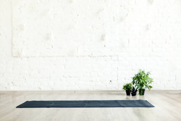istock Unrolled yoga mat laid on the floor in empty space with white brick wall background 1945475786