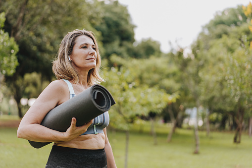 Mature woman going to practice physical exercise with exercise mat