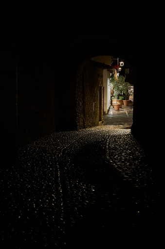 View through a tunnel to a dimly lit alleyway in the old town of Malcesine in Italy in the late evening