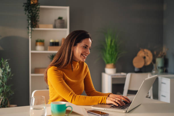 istock Woman using laptop while sitting at the desk in home office 1945526826