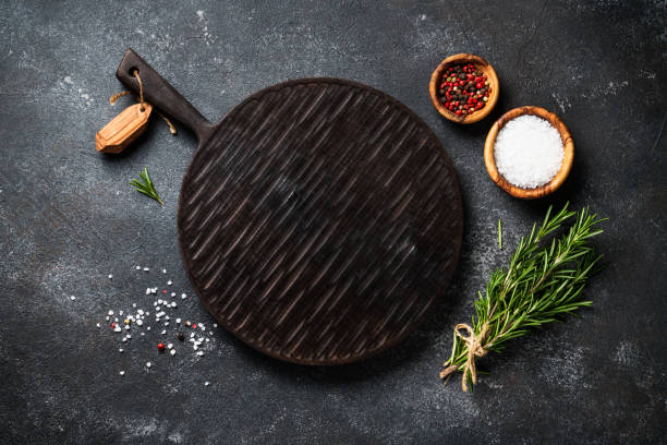 istock Spices and herbs with craft cutting board at black background. 1945536305