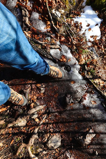 boots and legs with jeans of the adventurous hiker on the impervious path during the mountain excursion in winter