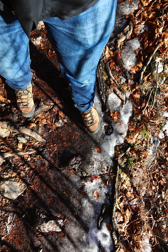 boots and legs with jeans of the adventurous hiker on the path during the mountain excursion in winter