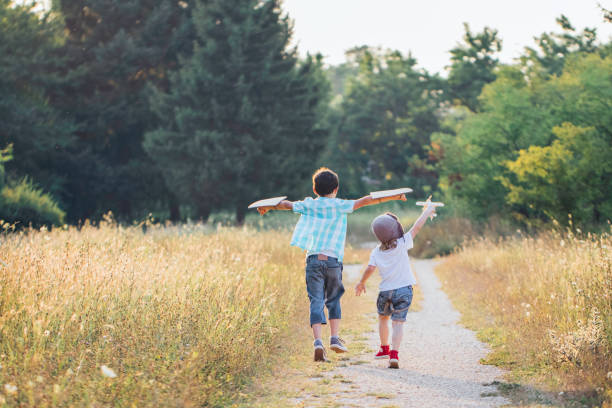 istock Happy children playing with toy airplane outdoors. Dreamlike, plane. 1945605208