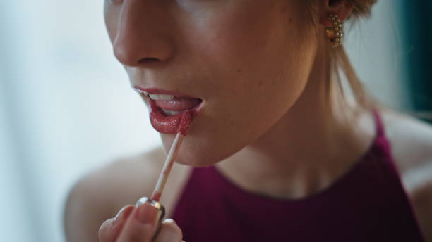 istock Closeup brush applying lipstick. Romantic girl doing makeup admiring herself. 1945609457
