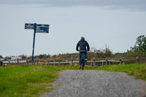 Gothenburg, Sweden - October 07 2023: Person om a bicycle passing a bike road sign.