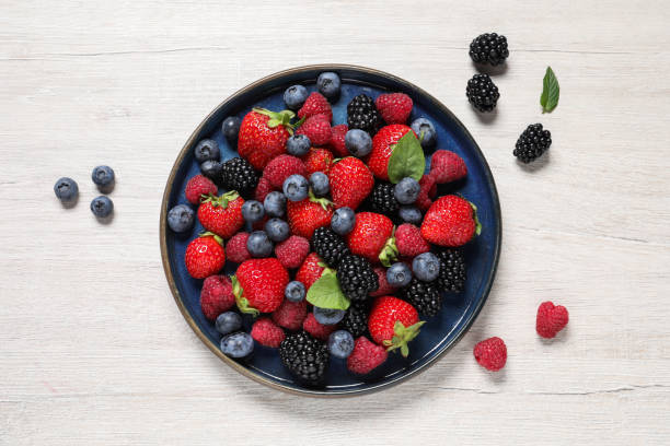 istock Different fresh ripe berries on light wooden table, flat lay 1945649310