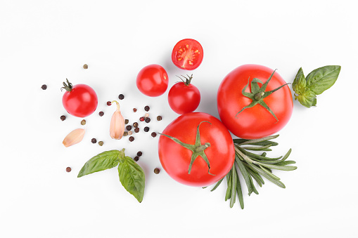 Flat lay composition with different whole and cut tomatoes on white background