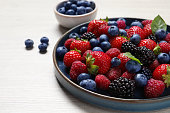 Different fresh ripe berries on light wooden table, closeup. Space for text