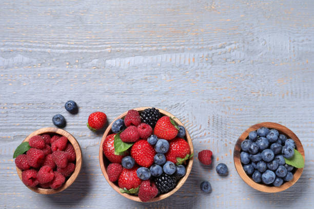 istock Different fresh ripe berries on light grey wooden table, flat lay. Space for text 1945651379