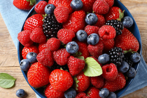 istock Different fresh ripe berries on wooden table, top view 1945651922