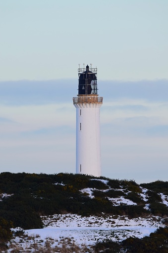 A distant view of Girdleness lighthouse in Aberdeen, Scotland in the snow.