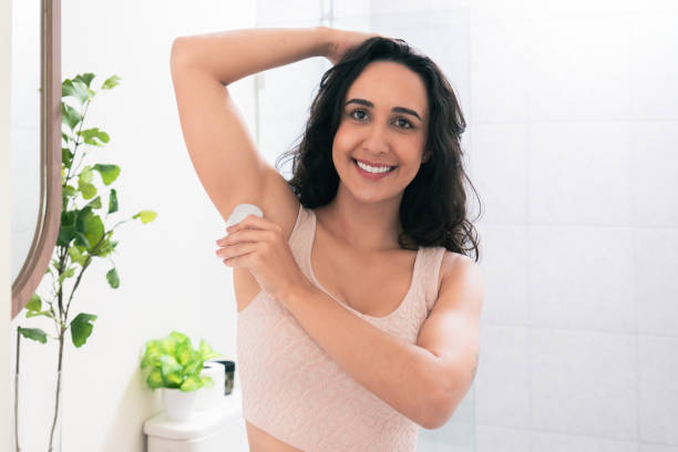 istock Smiling Latin American female waxing her armpit at her bathroom while looking at a camera. Happy woman caring about her body with beauty treatment for healthy lifestyle and positive emotion. 1945661521