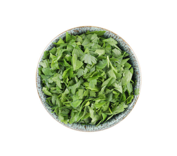 istock Chopped parsley leaves in bowl isolated on white, top view 1945668420