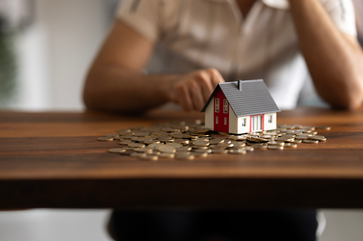 House model and coin holder money on the table for finance and banking concepts.