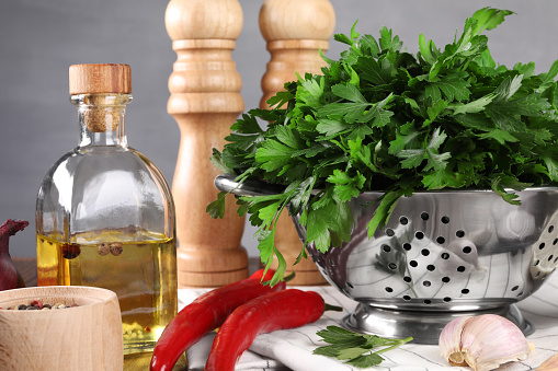Colander with fresh parsley, spices and other products on table, closeup