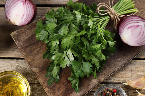 Board with fresh parsley and other products on wooden table