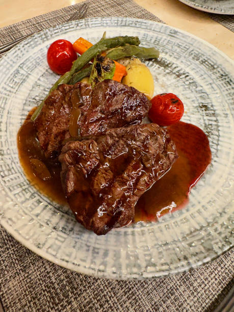 istock Delicious grilled beef steaks with sauce and vegetables served on table, closeup 1945681073