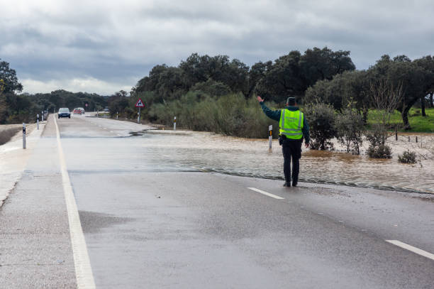 A Spanish Civil Guard officer directs traffic due to a water overflow and flooding caused by heavy rains. Badajoz, Spain. January 19, 2024. A Spanish Civil Guard officer directs traffic due to a water overflow and flooding caused by heavy rains. flood preparation stock pictures, royalty-free photos & images
