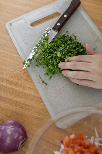 cutting cilantro leaves with knife on a cutting board, healthy ingredients for food, kitchen utensil, housework background