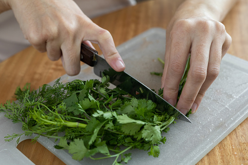 kitchen utensil, food preparation in kitchen, cutting cilantro leaves with knife on cutting board, healthy ingredients for food